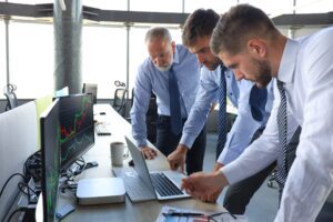 Group of modern business men in formalwear analyzing stock market data while working in the office.